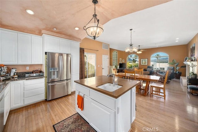 kitchen featuring sink, white cabinetry, a kitchen island with sink, stainless steel fridge with ice dispenser, and ceiling fan with notable chandelier