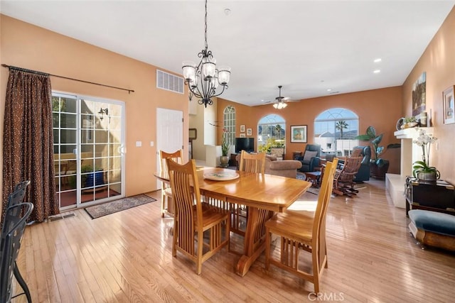 dining room featuring light wood-type flooring, ceiling fan with notable chandelier, and plenty of natural light