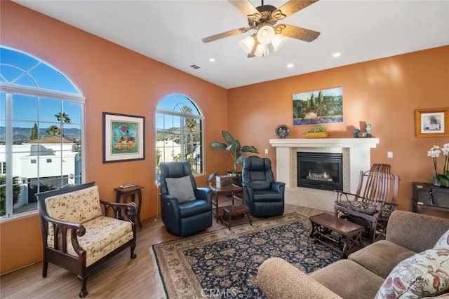 living room with ceiling fan, light hardwood / wood-style floors, and a tile fireplace