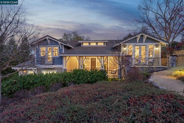 back house at dusk featuring a porch