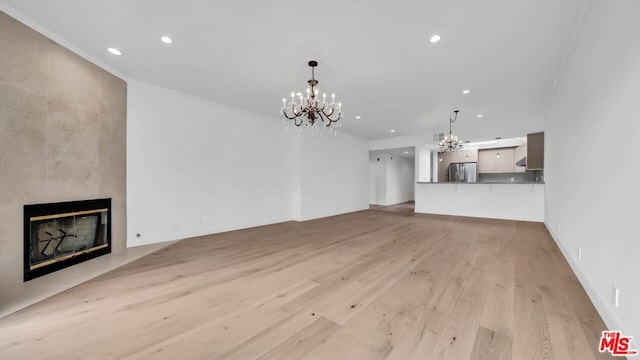 unfurnished living room featuring a fireplace, light hardwood / wood-style floors, and an inviting chandelier