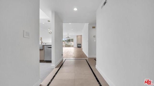 hall with an inviting chandelier and light tile patterned floors