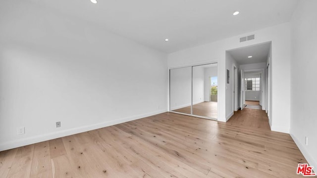 unfurnished bedroom with light hardwood / wood-style flooring and a closet