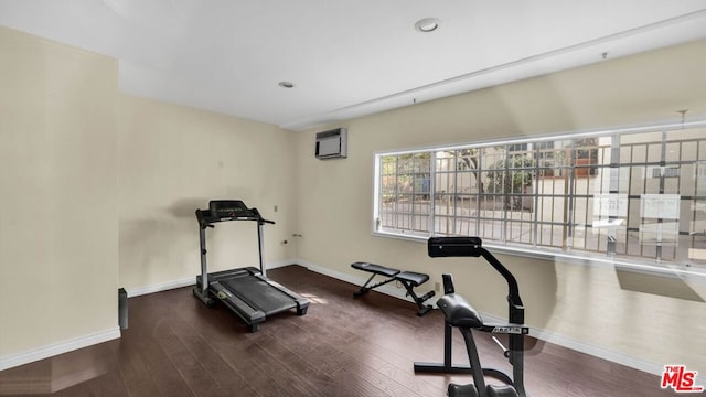 workout area with dark wood-type flooring and an AC wall unit