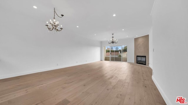 unfurnished living room with a fireplace, light wood-type flooring, and a chandelier