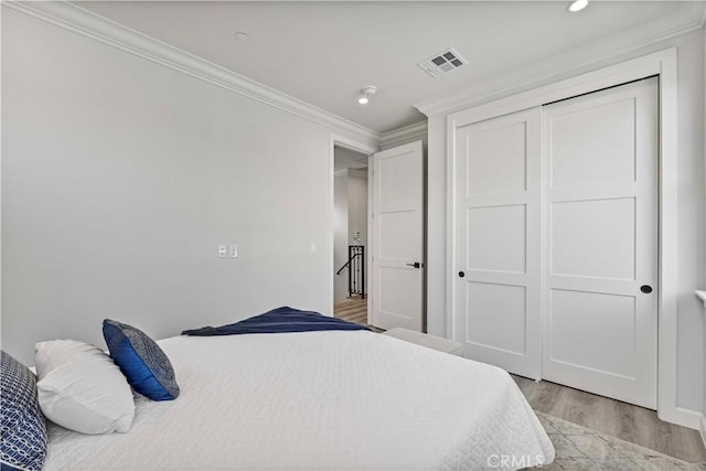 bedroom featuring crown molding, light wood-type flooring, and a closet