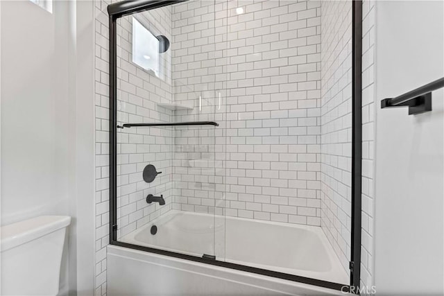 bathroom featuring enclosed tub / shower combo and toilet