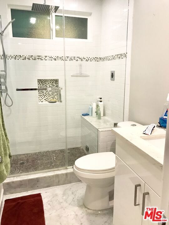 bathroom with toilet, a shower with door, and vanity