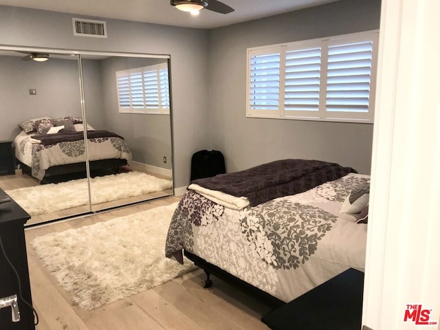 bedroom with ceiling fan, multiple windows, hardwood / wood-style floors, and a closet