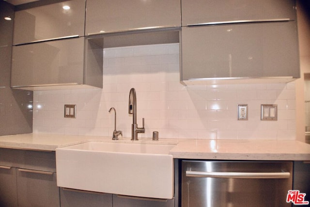 kitchen with light stone countertops, backsplash, and dishwasher