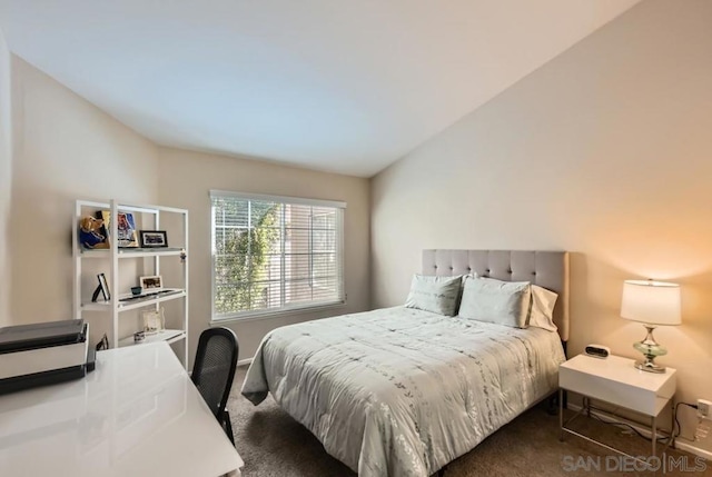 bedroom featuring lofted ceiling and dark carpet