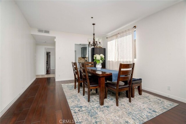 dining space featuring dark wood-type flooring and a notable chandelier