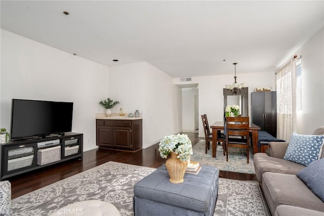 living room with dark hardwood / wood-style flooring, sink, and a chandelier