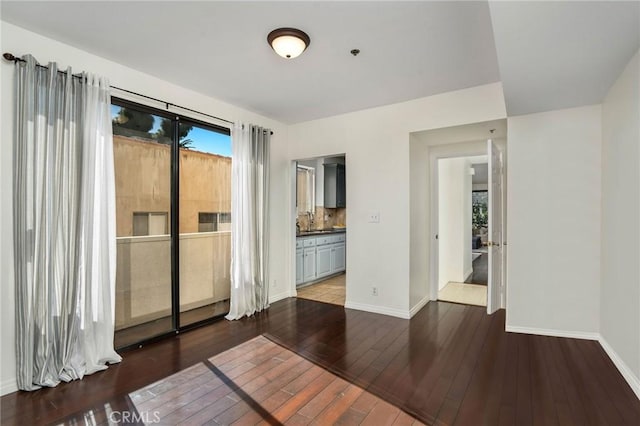 spare room featuring a healthy amount of sunlight, dark hardwood / wood-style flooring, and sink