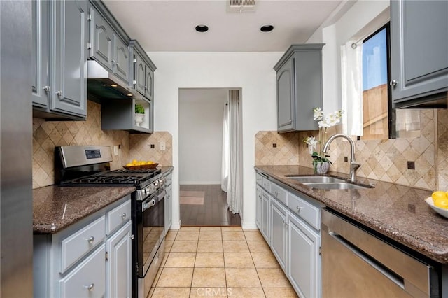 kitchen with light tile patterned flooring, appliances with stainless steel finishes, sink, gray cabinetry, and backsplash