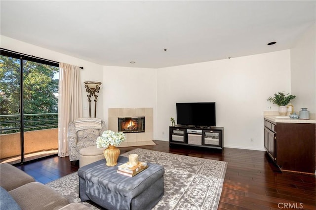 living room with dark wood-type flooring and a tile fireplace