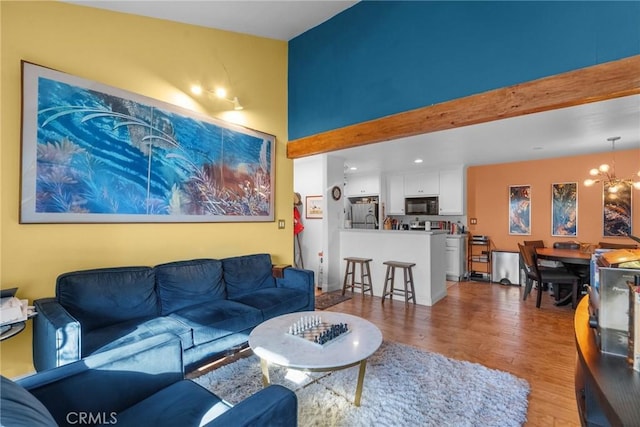 living room with hardwood / wood-style flooring, beam ceiling, and an inviting chandelier