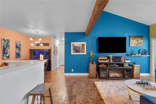 living room featuring wood-type flooring, a fireplace, vaulted ceiling with beams, and a notable chandelier