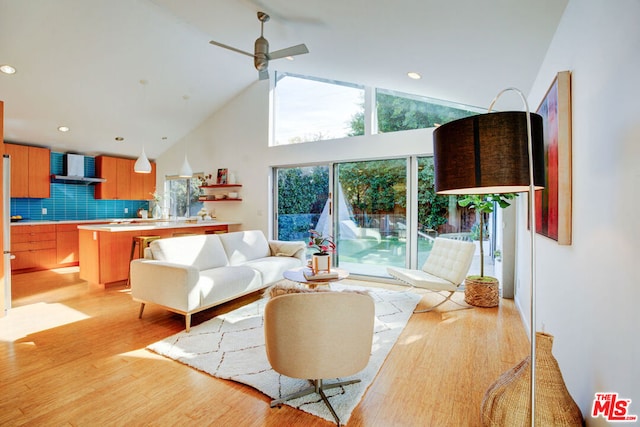 living room with ceiling fan, high vaulted ceiling, and light hardwood / wood-style floors