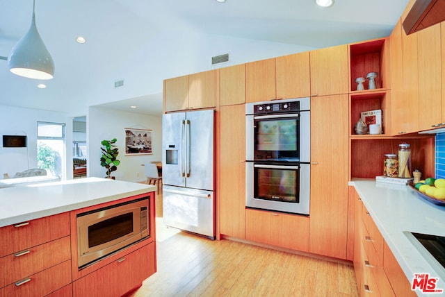 kitchen with hanging light fixtures, appliances with stainless steel finishes, lofted ceiling, and light wood-type flooring