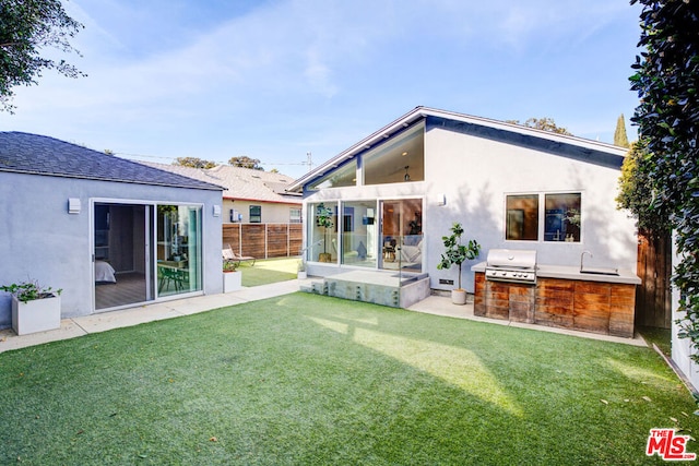 back of house with an outdoor kitchen and a lawn