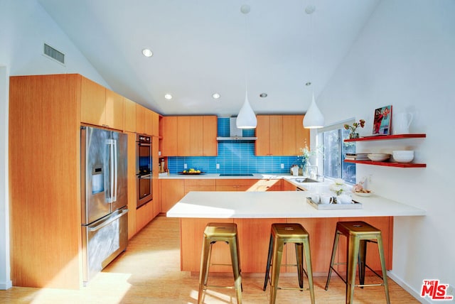 kitchen featuring vaulted ceiling, a kitchen breakfast bar, kitchen peninsula, stainless steel appliances, and decorative backsplash