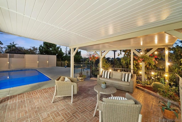 patio terrace at dusk with an outdoor living space and a fenced in pool