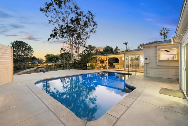 pool at dusk with a patio area