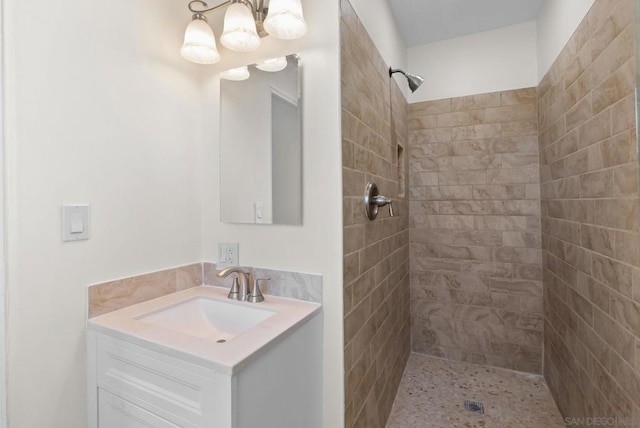 bathroom with vanity, an inviting chandelier, and tiled shower