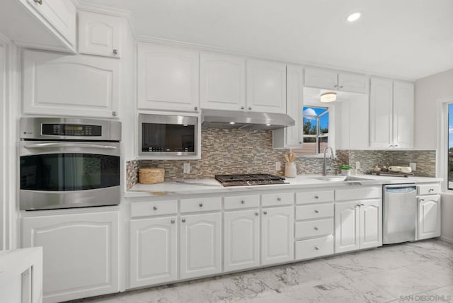 kitchen featuring decorative backsplash, sink, white cabinetry, and appliances with stainless steel finishes