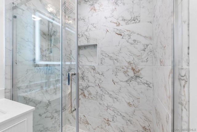 bathroom featuring a shower with shower door and vanity