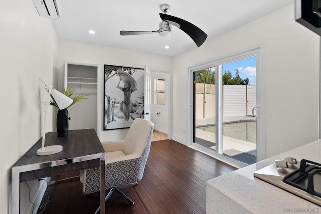 office area with dark wood-type flooring, ceiling fan, and a wall unit AC