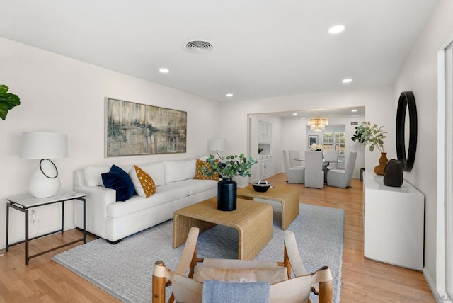 living room featuring a chandelier and light wood-type flooring