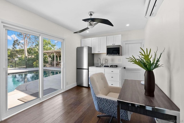 kitchen featuring ceiling fan, appliances with stainless steel finishes, a wall mounted air conditioner, white cabinets, and sink