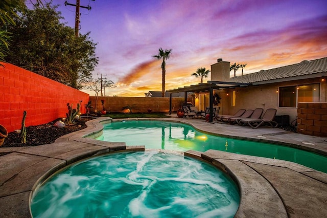 pool at dusk with an in ground hot tub, a patio area, and a pergola