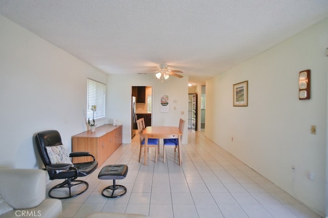 dining area with light tile patterned floors, ceiling fan, and a textured ceiling