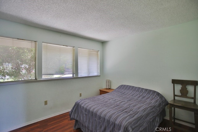 bedroom with dark wood-style floors, baseboards, and a textured ceiling