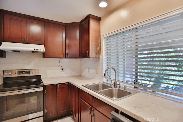 kitchen featuring tasteful backsplash, light countertops, stainless steel range with electric cooktop, a sink, and under cabinet range hood