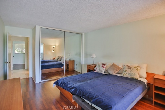 bedroom with a textured ceiling, a closet, and dark wood finished floors