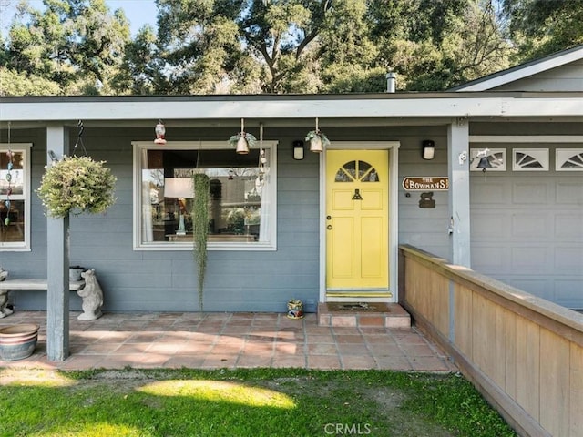 doorway to property with a garage and a porch