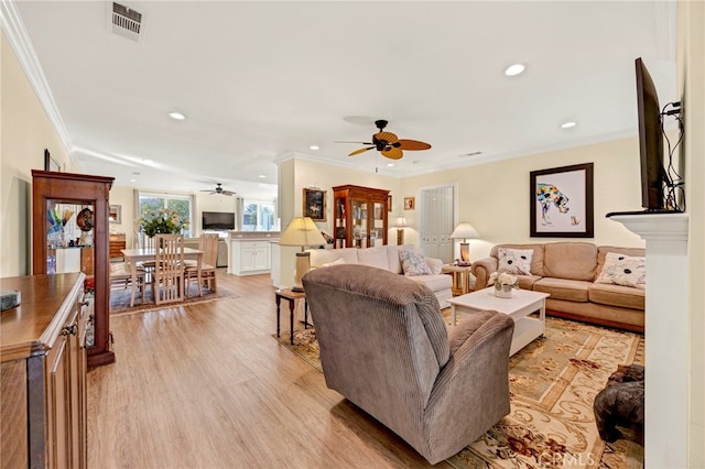 living room featuring light hardwood / wood-style floors, crown molding, and ceiling fan