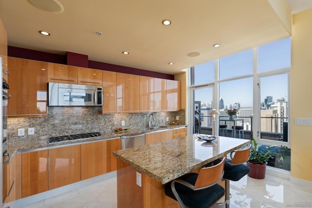 kitchen featuring a breakfast bar area, stainless steel appliances, light stone counters, and a center island