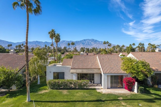 rear view of property featuring a patio, a mountain view, and a lawn