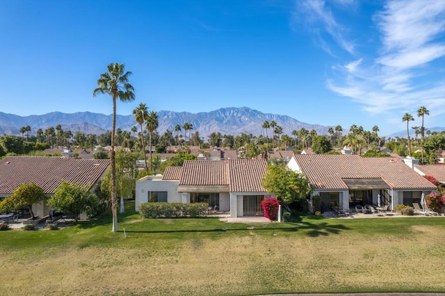 back of property featuring a mountain view and a lawn