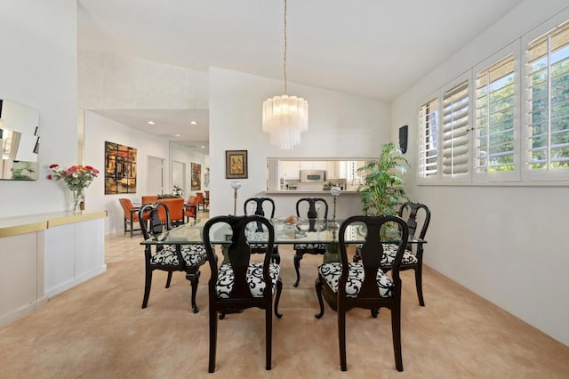 dining area with high vaulted ceiling, light carpet, and an inviting chandelier