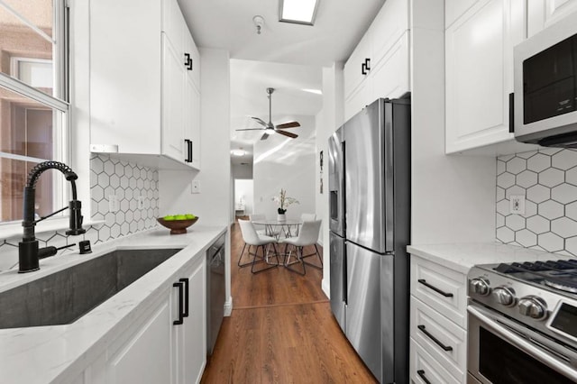 kitchen featuring wood-type flooring, white cabinetry, stainless steel appliances, decorative backsplash, and sink