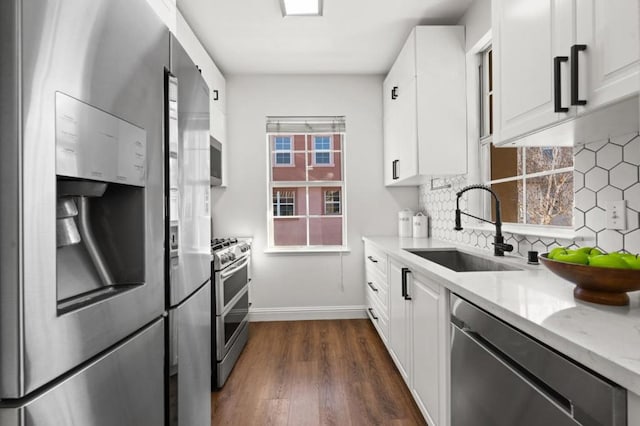 kitchen featuring light stone countertops, white cabinets, dark hardwood / wood-style flooring, stainless steel appliances, and sink