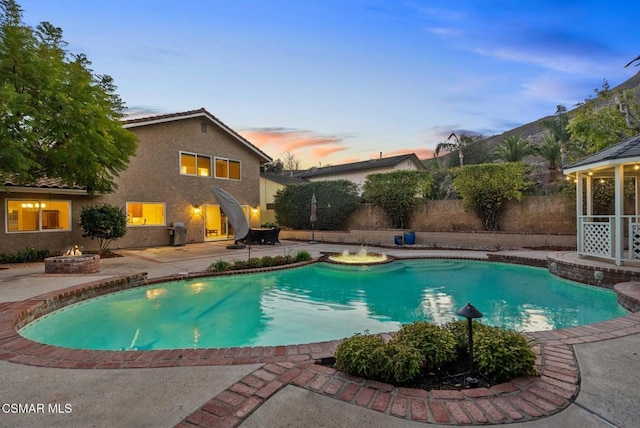 pool at dusk with a patio area and an outdoor fire pit