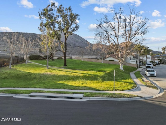 surrounding community with a lawn and a mountain view