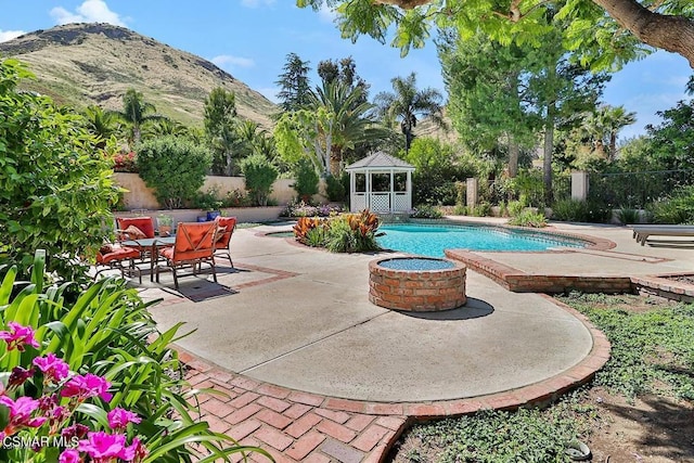 view of pool featuring a patio area, a gazebo, a mountain view, and an outdoor fire pit